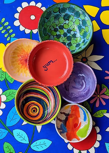 Colorful, patterned bowls arranged on a vibrant floral tablecloth.