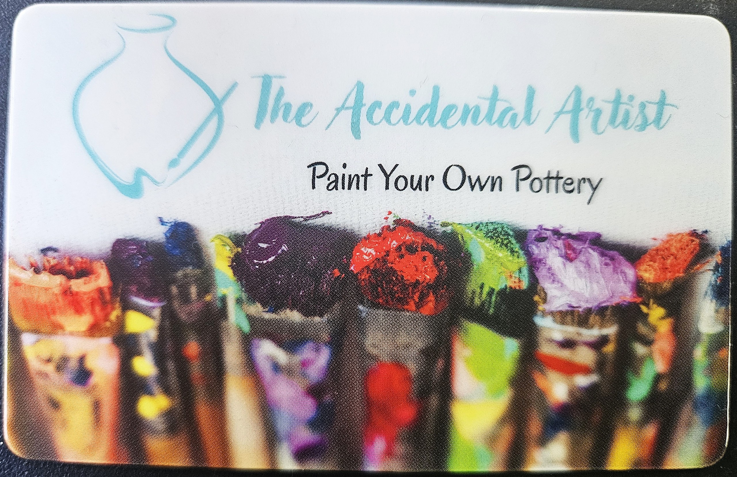 Art store logo with paintbrushes and text 'The Accidental Artist: Paint Your Own Pottery'.
