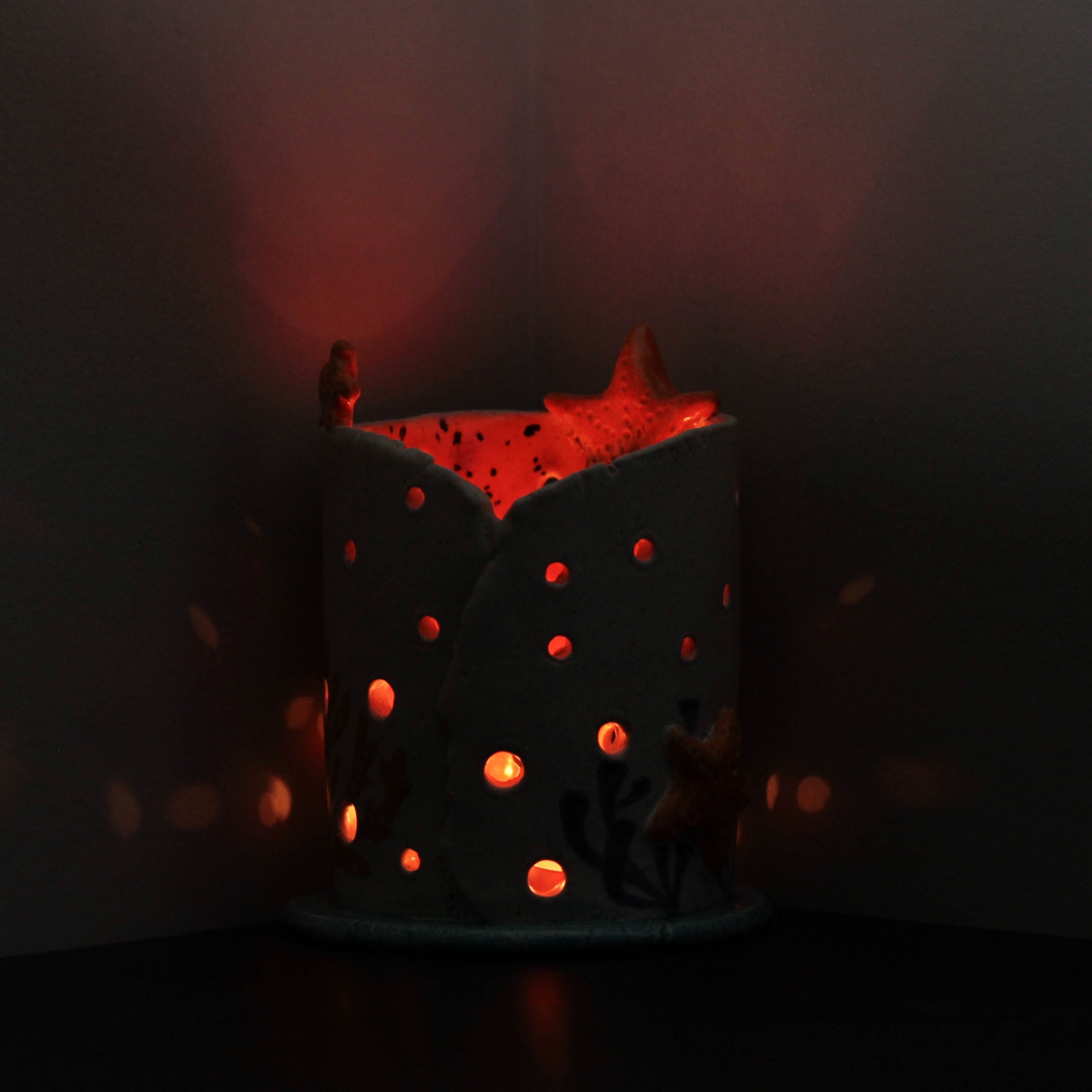 Decorative candle holder with starfish, glowing light.
